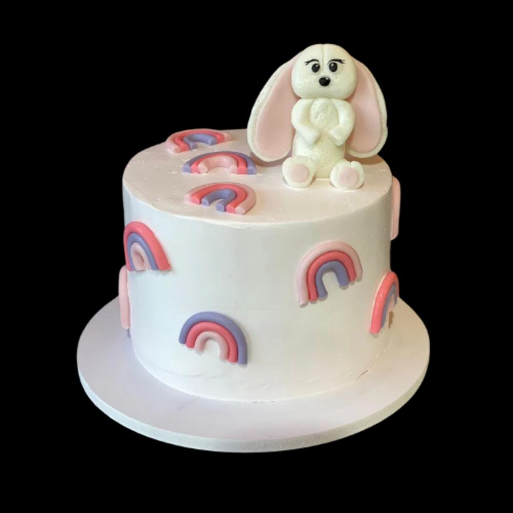 White cake with a rainbow and a white teddy bearundefined
