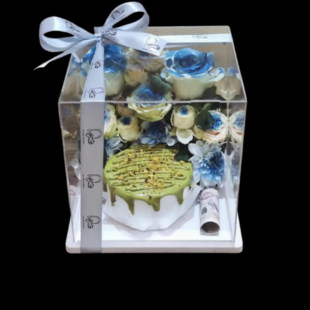 Pistachio cream cake with blue roses in a transparent box
