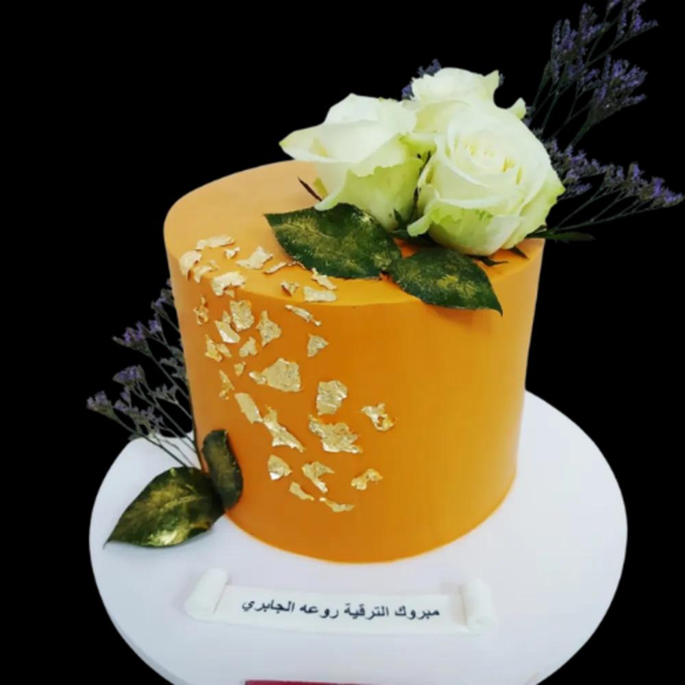 Cake decorated with gold leaf with white roses and leavesundefined