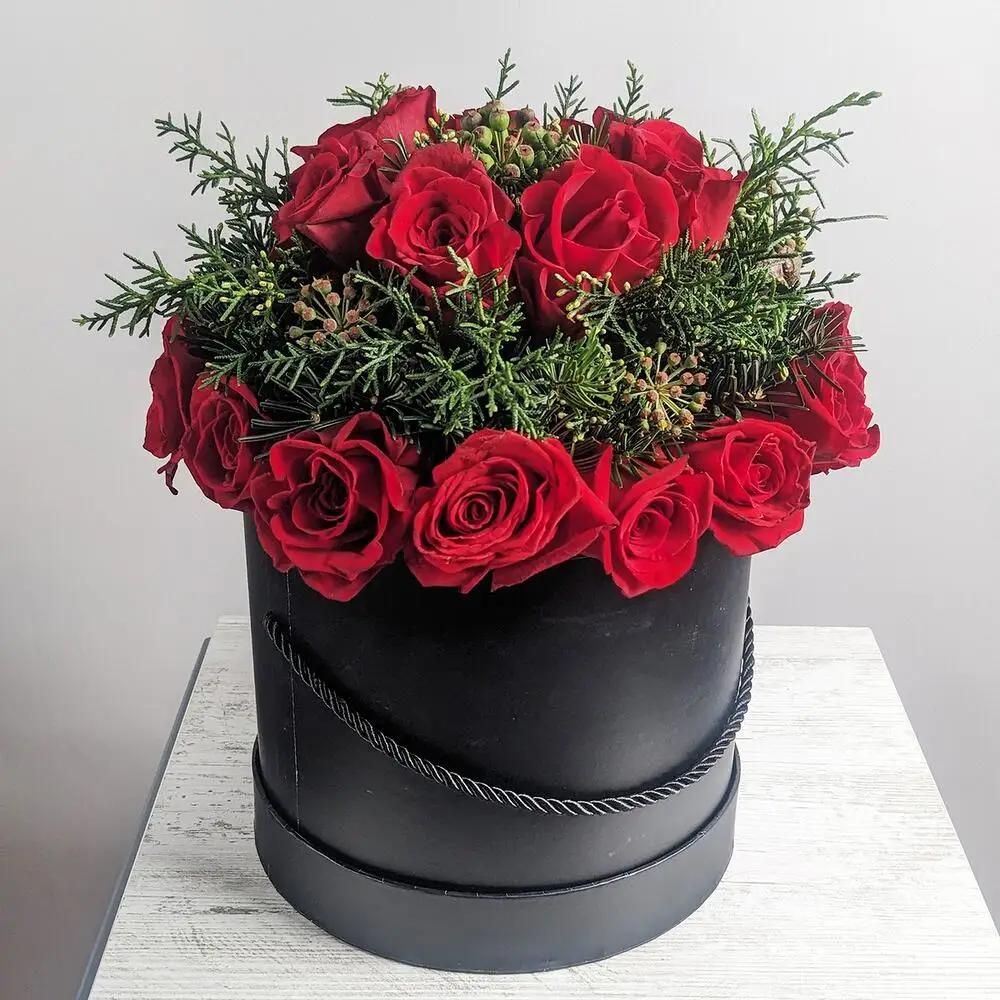 Maroon roses with coniferous branches in a black box