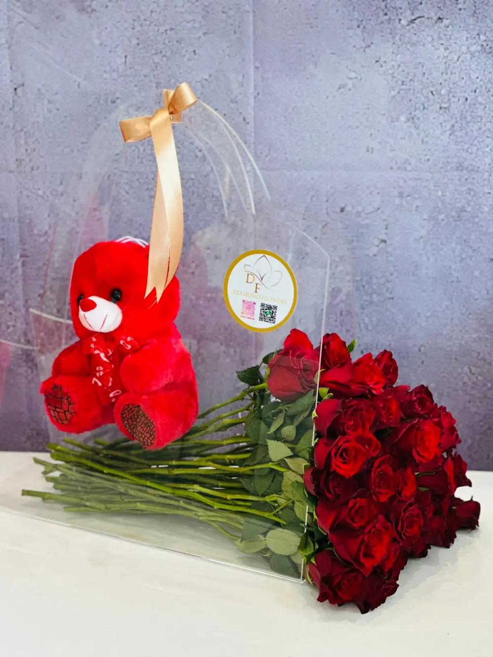 An acrylic bag with red roses and a teddy bear